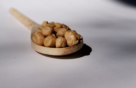 large peas on a wooden spoon on a white background