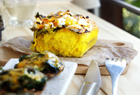 cheese bread with greens bacon and feta on a tableの写真素材