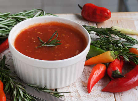 bowl of tomato hot sauce with peppers, rosemary and cutleryの写真素材