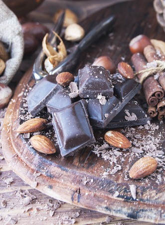 pieces of chocolate with nuts and cinnamon on a wooden table, with oriental tea, spices, selective focusの写真素材
