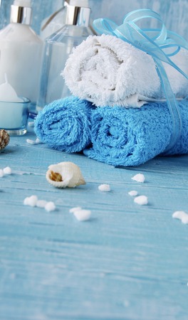 White flowers lying on a blue wooden board with shell and candle Spa setの写真素材