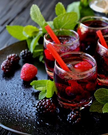 berry juice in a glass with berries, ice and mint, selective focusの写真素材