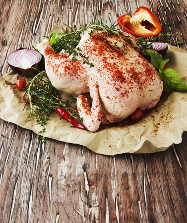 raw chicken with herbs spices ingredients, ready for cooking, on a wooden table, selective focusの写真素材