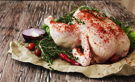 raw chicken with herbs spices ingredients, ready for cooking, on a wooden table, selective focusの写真素材