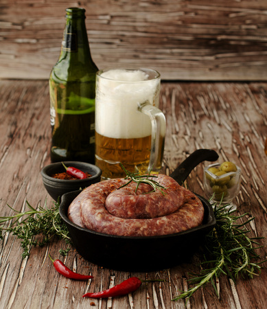 raw beef sausages on a cast-iron pan with rosemary and spices on a wooden table, South African boereworsの写真素材
