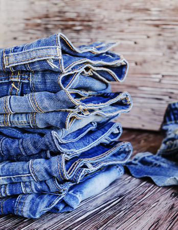 stack of jeans lying on a wooden table, selective focusの写真素材