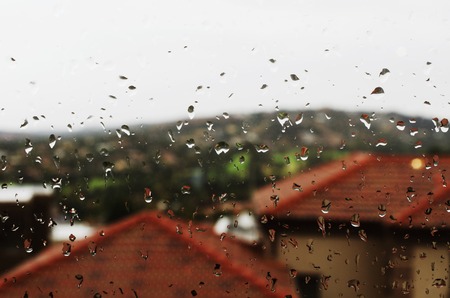 glass with rain drops on a background of houses with red roofs, selective focus, backgroundの写真素材