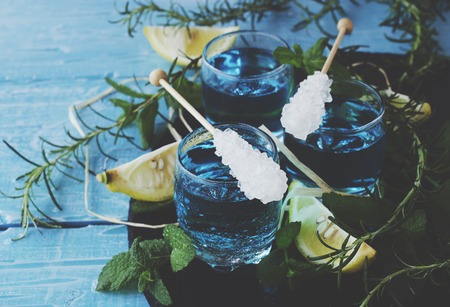 Blue curacao liqueur or sambuca with lemon on the wooden table, selective focusの写真素材