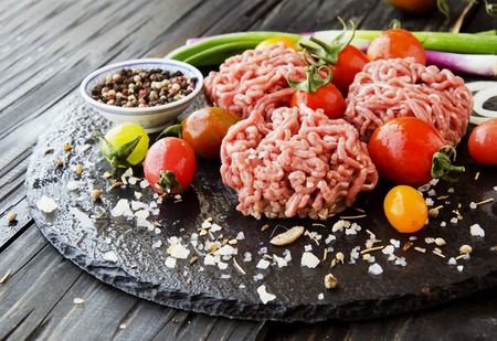 raw minced meat, vegetables with salt and spices, on a black background, selective focus, space for textの写真素材