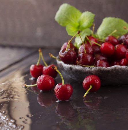 ripe cherries or cherry with drops of water on black stone background, selective focusの写真素材
