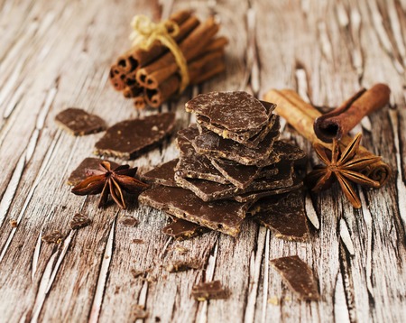 pieces of chocolate with cinnamon and anise stars on a wooden table, selective focusの写真素材