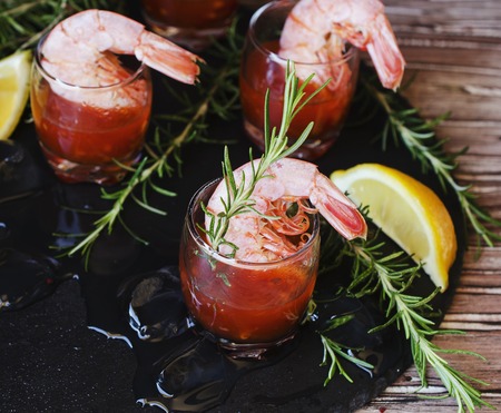 appetizer of shrimp cocktail with rosemary and sauce in cups on a wooden table, selective focusの写真素材