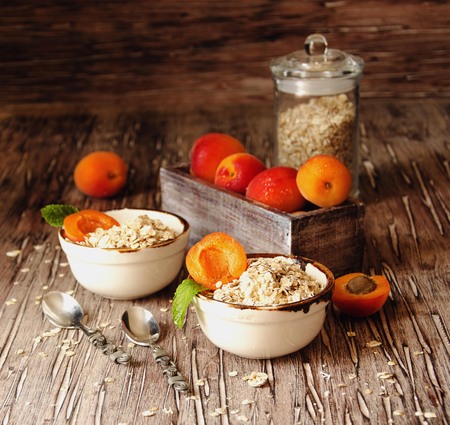 healthy breakfast of muesli and apricot and cream in ceramic bowls on a wooden table, rustic, selective focus, space for textの写真素材