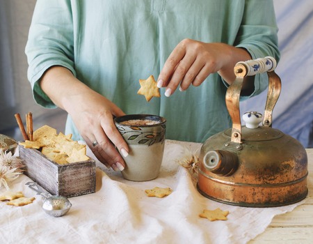 woman's hands holding a cup of cocoa over the dinner table, rustic style, selective focusの写真素材