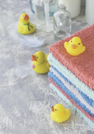 stack of towels with yellow rubber bath ducks and means for bathroom on white marble background, space for text, selective focusの写真素材