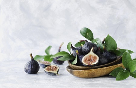 dark blue Fresh figs in a wooden bowl on a white marble table, selective focusの写真素材