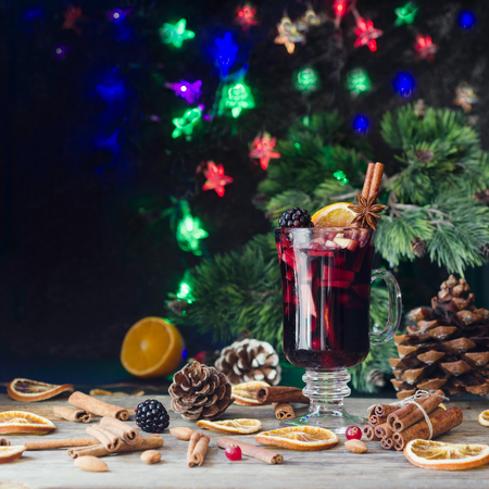 A glass of hot mulled wine for the new year with ingredients for cooking, nuts and Christmas decorations, a Christmas card, selective focus, space for text, a low keyの写真素材