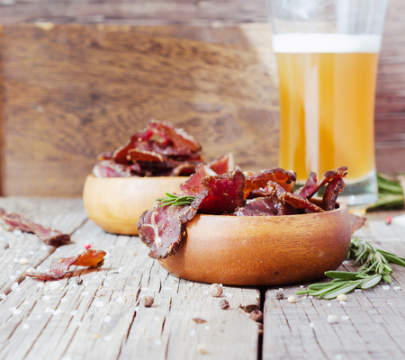 jerked meat, cow, deer, wild beast or biltong in wooden bowls on a rustic table, selective focusの写真素材