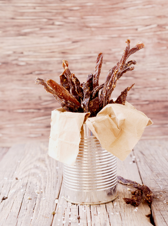 jerked meat, cow, deer, wild beast or biltong in kraft paper bowls on a rustic table, selective focusの写真素材