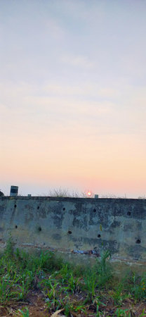Old concrete wall with green grass and blue sky at sunset background.の写真素材