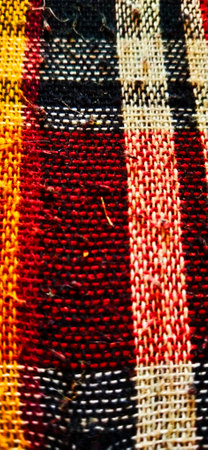 Close up detail of a hand woven fabric texture background in brown and red