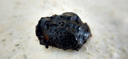 A closeup shot of a black coal on a white stone surface