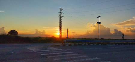 sunset on the road with silhouette of high voltage pole in Thailand