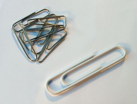 One white paper-clip distinguish from another metallic clipsの写真素材