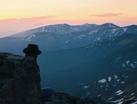 mountain sunset landscape with man, who sit near the fortress and look into the distanceの写真素材