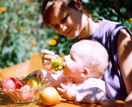 Mother and child with fruit in flowering summer garden (softfocus)