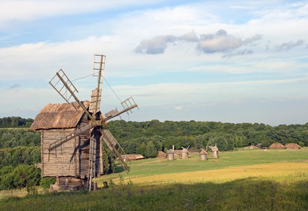Old historical obsolete windmill and village with another windmills far awayの写真素材