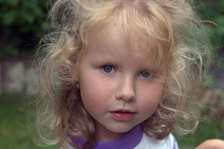attentive mischievous little girl in garden (with water drops in hair)の写真素材