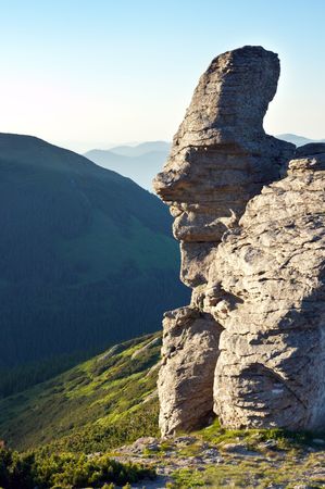 Big stony figure in human face form on evening mountain ridgeの写真素材