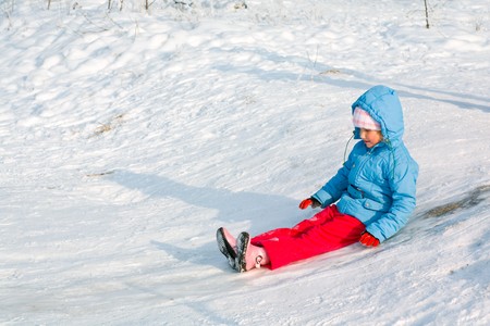 Small girl in winter snow covered courtyardの写真素材