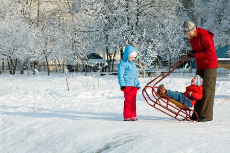 Happy family (mother with small boy and girl) on winter snow covered courtyard near houseの写真素材