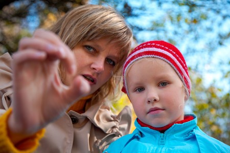 mother with small girl in golden autumn city parkの写真素材