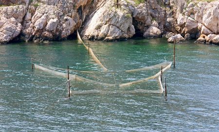 fishing nets in sea near rocky coastlineの写真素材