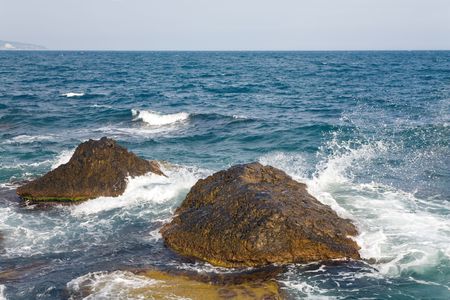 Stony sea coastline  and wave with splashesの写真素材