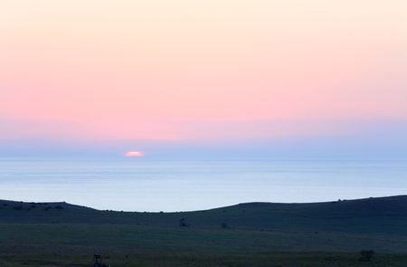 Coastal meadow sunset view with oil produce tower in the distance,の写真素材