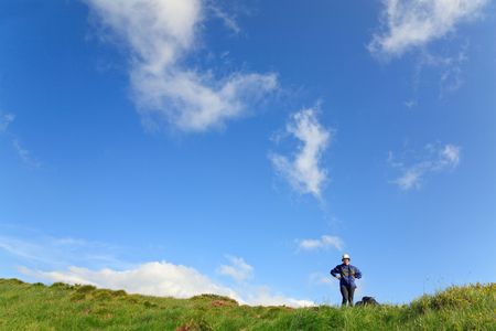 Happy smiling tourist (young woman) on summer mountain slope