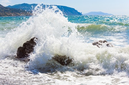 Sea surf wave break on coastline and Meganom cape on horizon right (Crimea, Ukraine)の写真素材