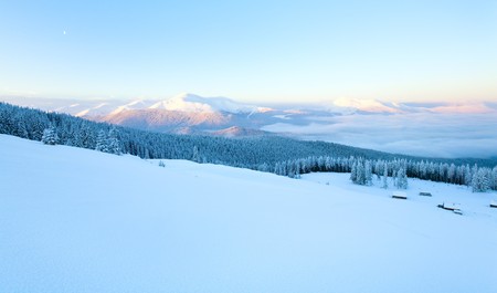 Sunrise and winter mountain landscape with sheds group on slope. View from Kukol Mount.  (Carpathian Mountains, Ukraine)の写真素材