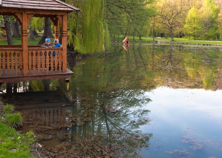 Two children in belvedere near beautiful spring lake in the park.の写真素材