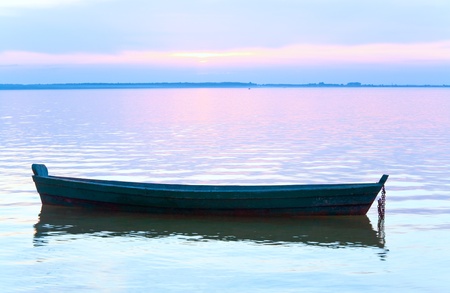 Sunset and old wooden fishing boat on summer lake bank (Svityaz, Ukraine)の写真素材