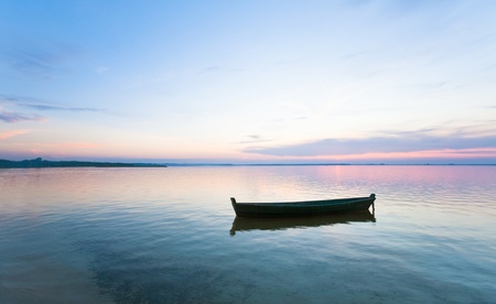 Sunset and old wooden fishing boat on summer lake bank (Svityaz, Ukraine)の写真素材