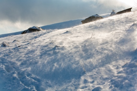 Winter snowy and windy mountain overcast view with sheds behindの写真素材