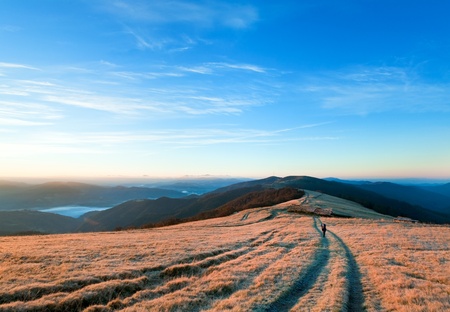 Sunrise Carpathian Mountains (Ukraine) autumn landscape with country road and tourist on.の写真素材