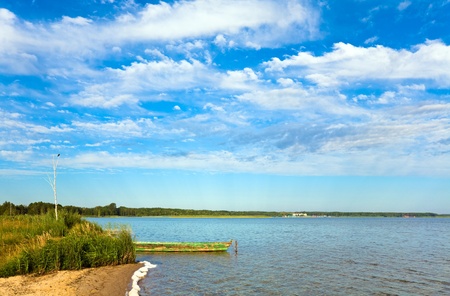 Summer rushy lake view with wooden boat near shoreの写真素材