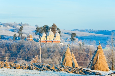 Autumn morning hoarfrost on mountain village outskirts pasture and haystack
