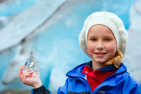 Portrait happy girl with piece of ice in hand on Nigardsbreen glacier background (Norway)の写真素材